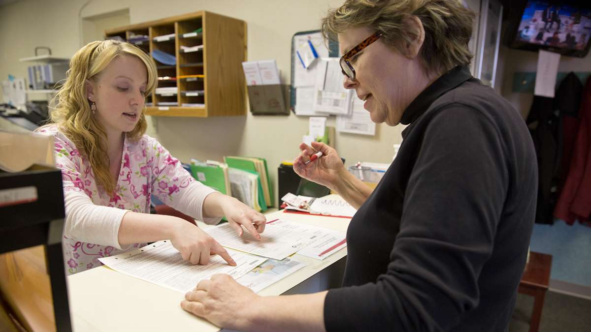 Receptionist Jennifer Baker advises Suzanne Cloud on health insurance forms before her appointment at Cooper Medical Services. (Lindsay Lazarski/WHYY)