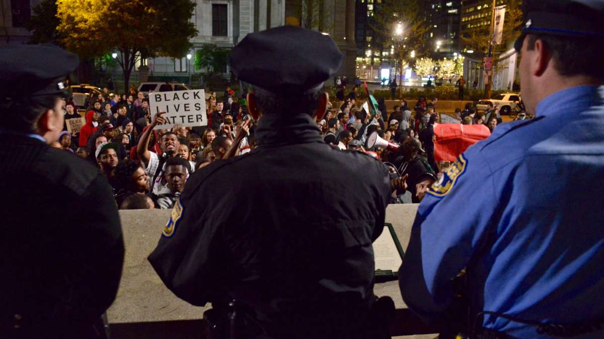  Police officers watch as protesters pass by and briefly stop across Philadelphia's City Hall Thursday night. (Bastiaan Slabbers/for NewsWorks)   