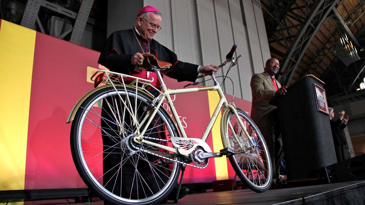  At the opening ceremony of the World Meeting of Families Tuesday, Mayor Michael Nutter presents the city's gift for Pope Francis -- a bicycle, received on the pope's behalf by Archbishop Charles Chaput. (Emma Lee/WHYY) 