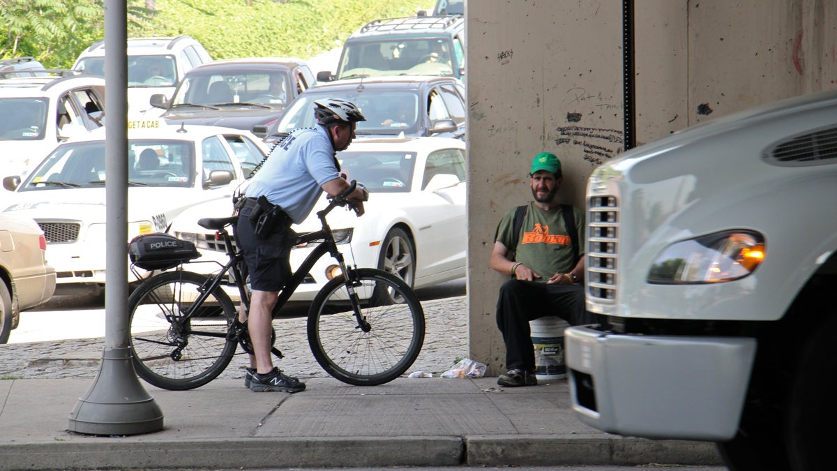 A Philadelphia police officer stops at the I-676 off ramp to Sixth Street to remind a panhandler of an upcoming court date.