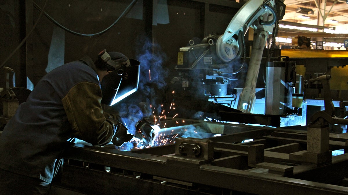 A human welder works beside a robot welder at PTR Baler in Port Richmond. (Emma Lee/WHYY)