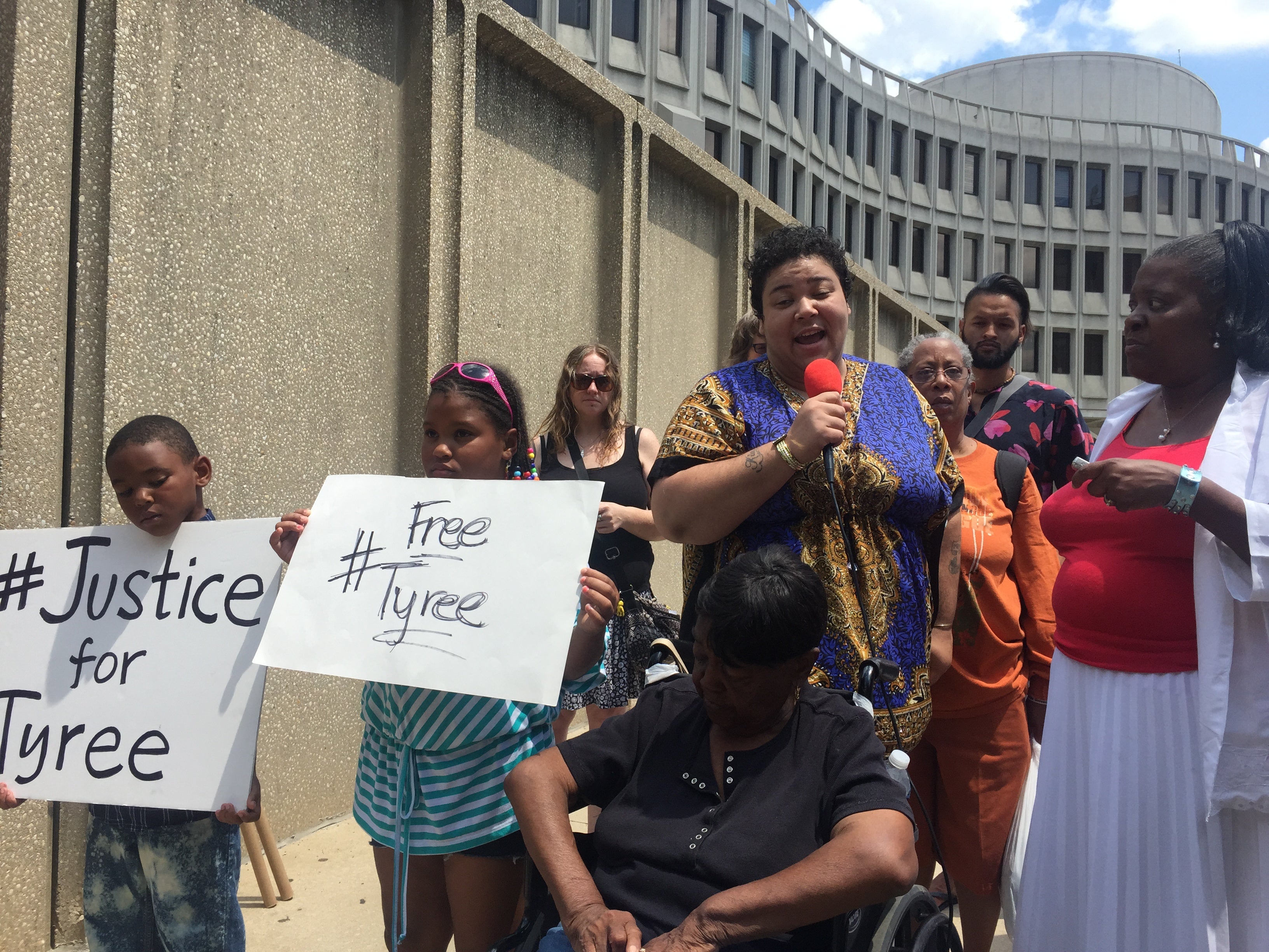  Tyree Carroll's sister-in-law Kia-Marie Benton speaks at a rally  Friday. She joined by Carroll's nephew and niece, holding signs, and other supporters. (Bobby Allyn/WHYY)  