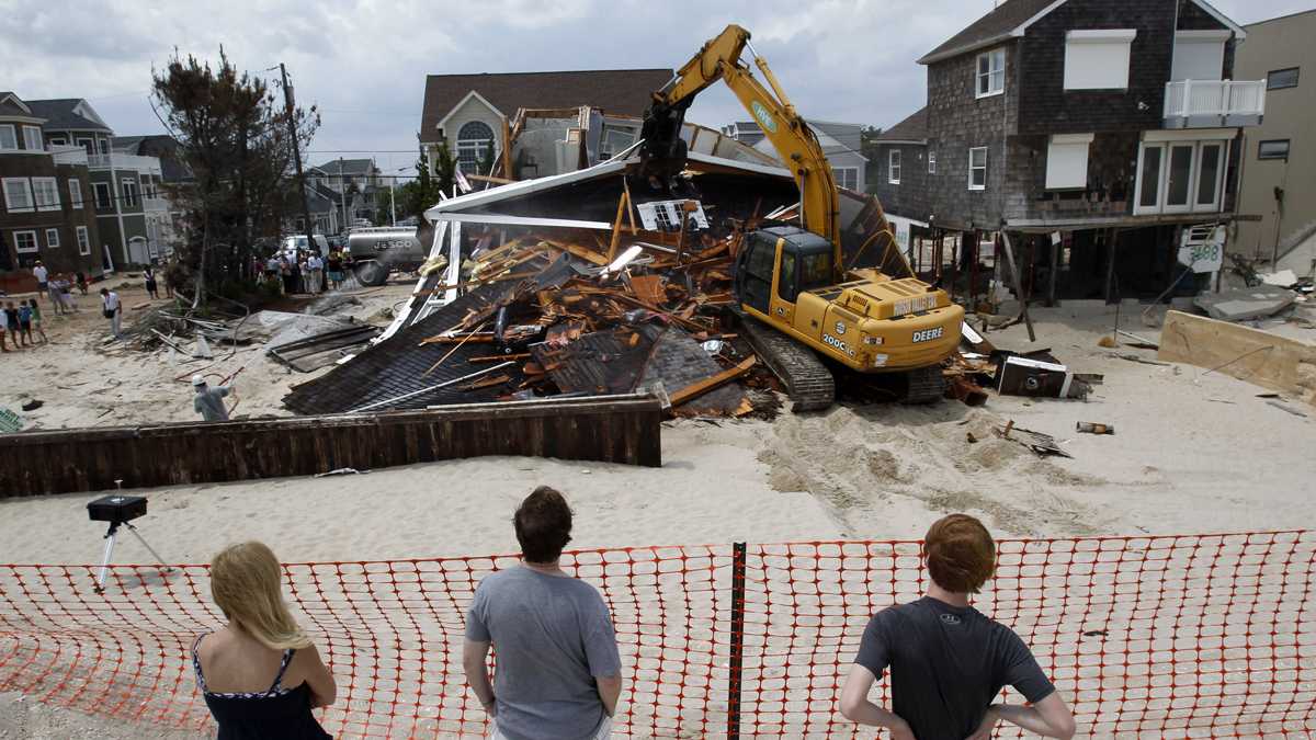  People watch from the beach Wednesday, July 10, 2013, as a home severely damaged by Superstorm Sandy is demolished in the Normandy Beach section of Toms River, N.J. (Mel Evans/AP Photo, file) 