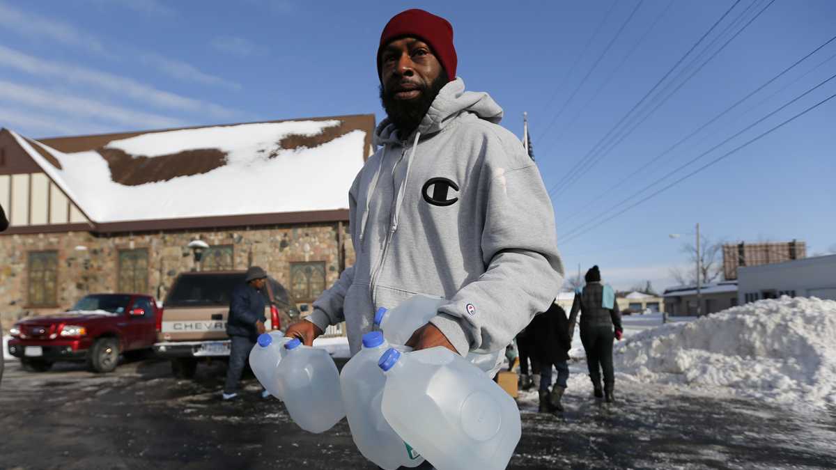  Lemott Thomas carries free water being distributed at the Lincoln Park United Methodist Church in Flint, Michigan. (AP Photo/Paul Sancya) 