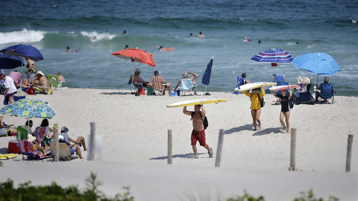 Surfers carry their surfboards across the beach as they call it a day