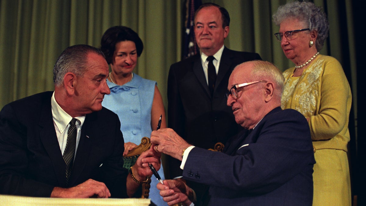  President Lyndon B. Johnson signed the bill creating Medicare and Medicaid at the library of former President Harry Truman, who was in attendance, on July 30, 1965. (Photo courtesy of Truman Library)  