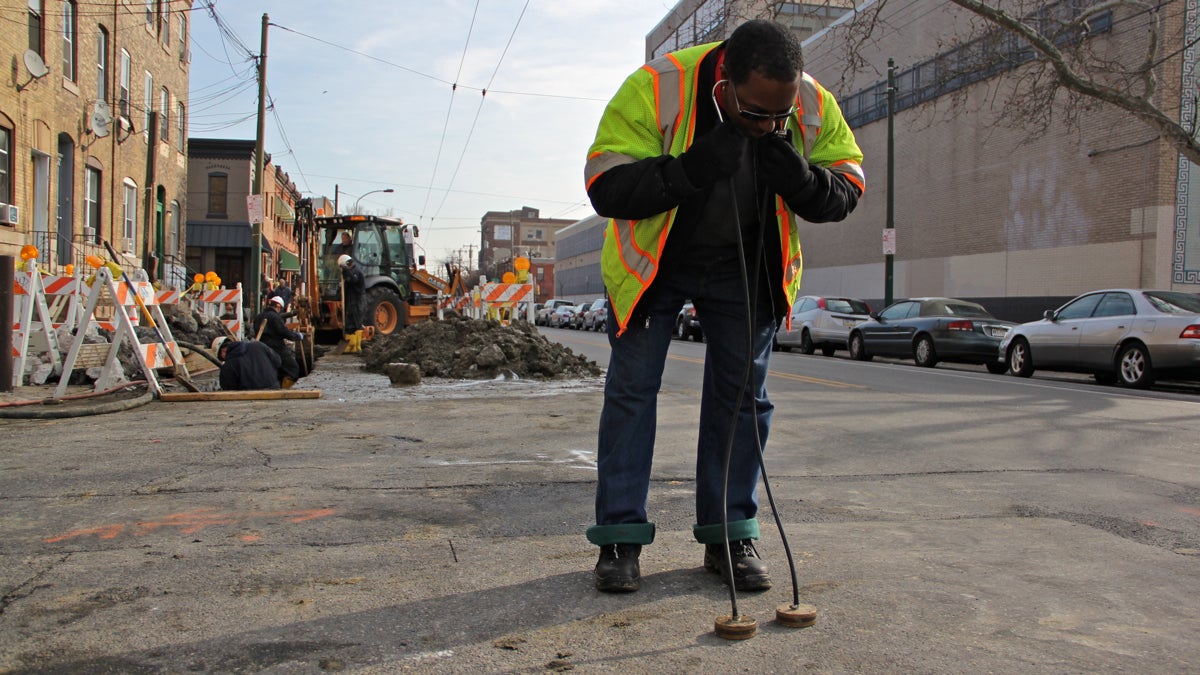 Philadelphia Water Department leak detector Jassen Smallwood uses a pair of geophones to detect a leak. (Emma Lee/for WHYY)