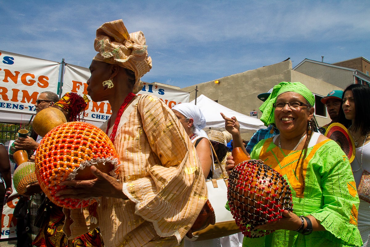  Women play the sekere, or shaker, a traditional instrument of the Yoruba people of Nigeria, as they make their way toward the South Street Bridge during a procession at the Odunde Festival. (Brad Larrison/for NewsWorks) 