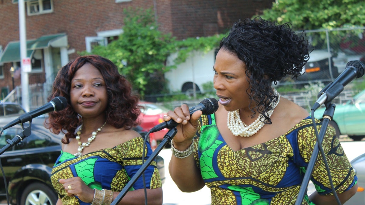  Zaye Tete (left) and Marie Nyenabo perform with the Liberian Women's Chorus for Change at Bluebell Triangle Park on Woodland Avenue. (Elisabeth Perez-Luna/WHYY) 