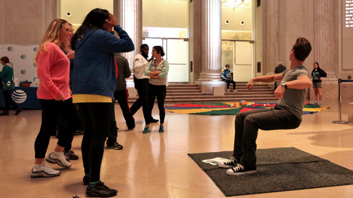 Max Major sits in an invisible chair at the Franklin Institute as people watch in disbelief. (Photo credit ©Darryl W. Moran Photography/The Franklin Institute)
