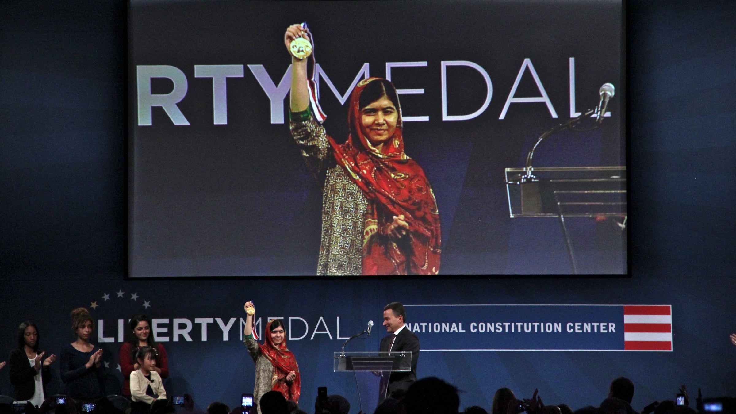  Malala Yousafzai holds up the Liberty Medal after receiving it from National Constitution Center President Jeffrey Rosen. (Emma Lee/WHYY) 