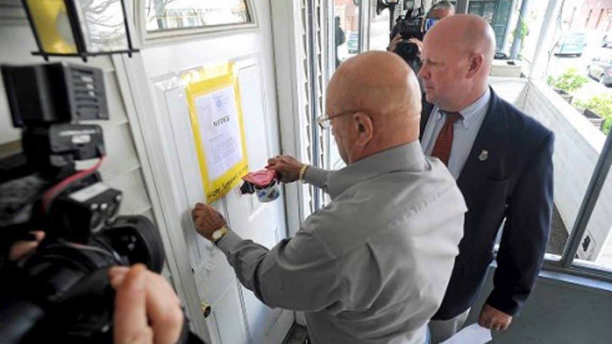  Wilkes-Barre City Code Enforcement Officer Frank Kratz, (left), and Mayor Tom Leighton post a closure notice (Mark Moran/The Citizens’ Voice)  