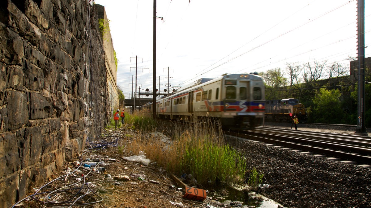  A SEPTA train passes as the Mural Arts installation crew paints one of the seven sites of Katharina Grosse's psychylustro in Philadelphia, Pa.  (Nathaniel Hamilton/For NewsWorks)  