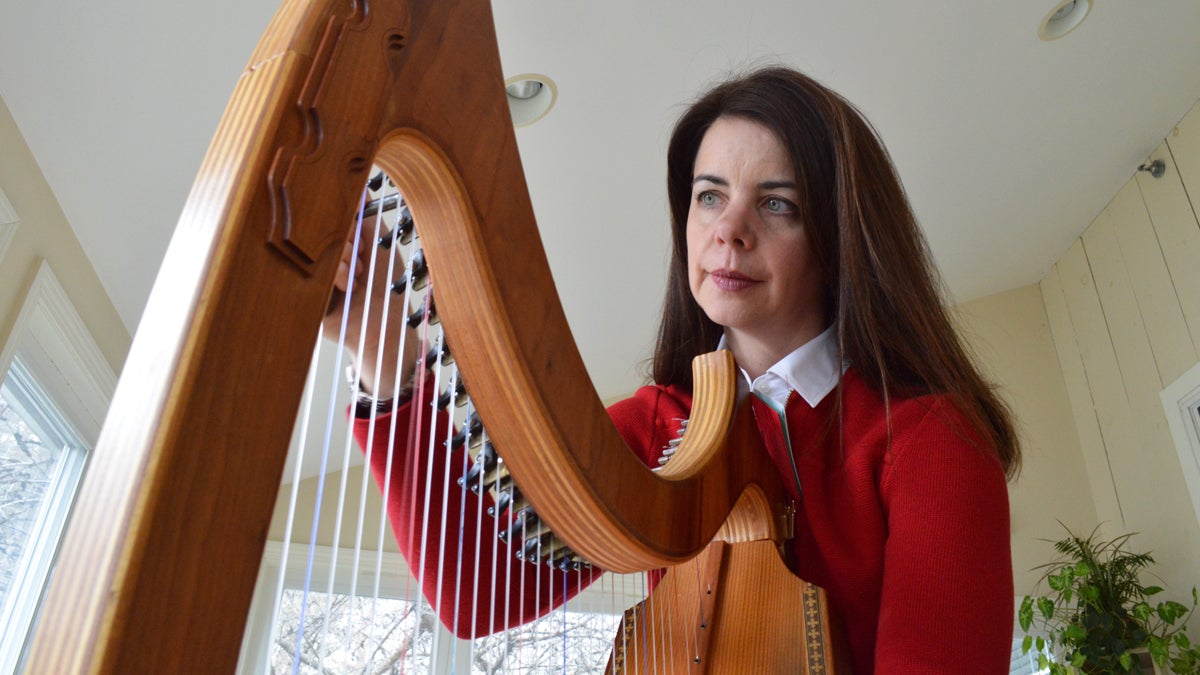 Jennifer Hollis tunes her harp before playing for palliative care patients. (Paige Pfleger/WHYY)