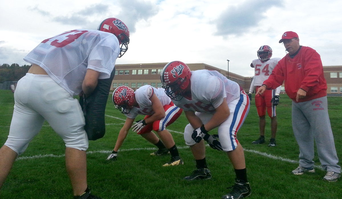 Head football coach Mark Schmidt (right) runs a drill with the Neshaminy High School Redskins. (Aaron Moselle/WHYY) 