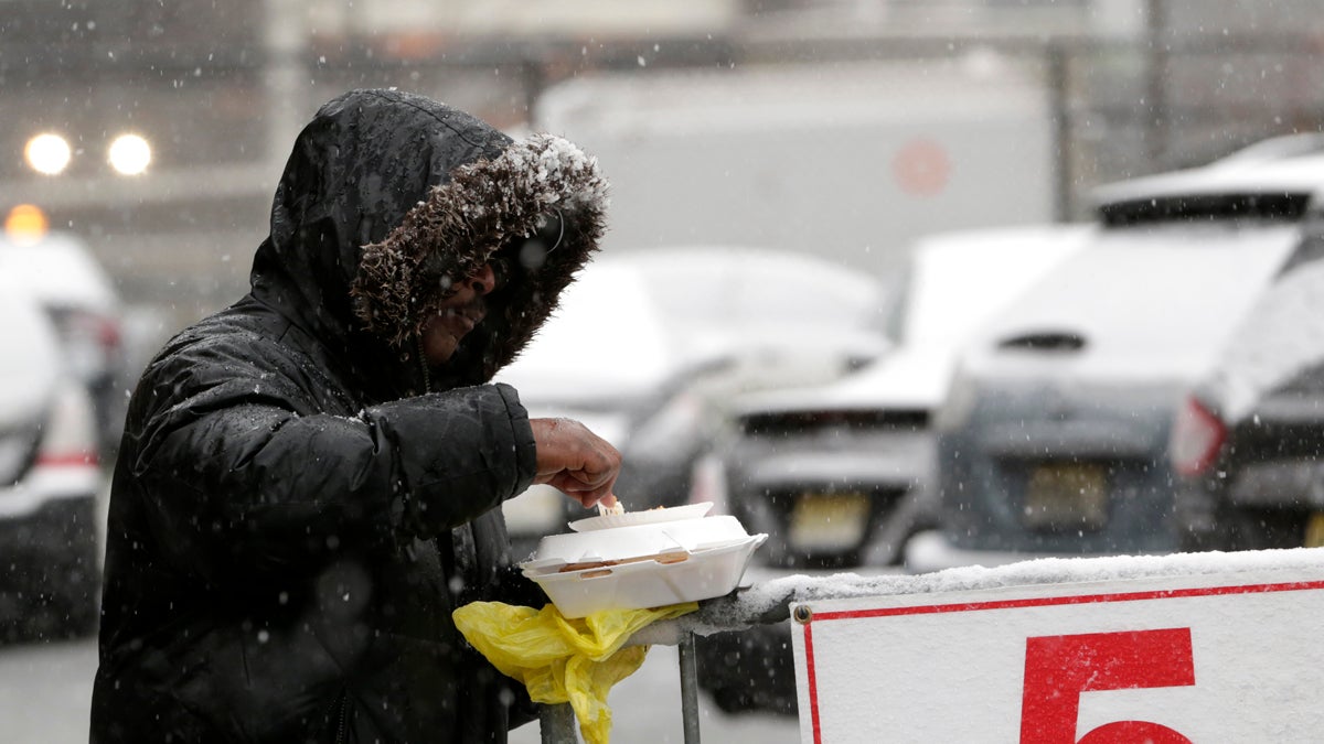 Snow falls over a homeless person in Newark