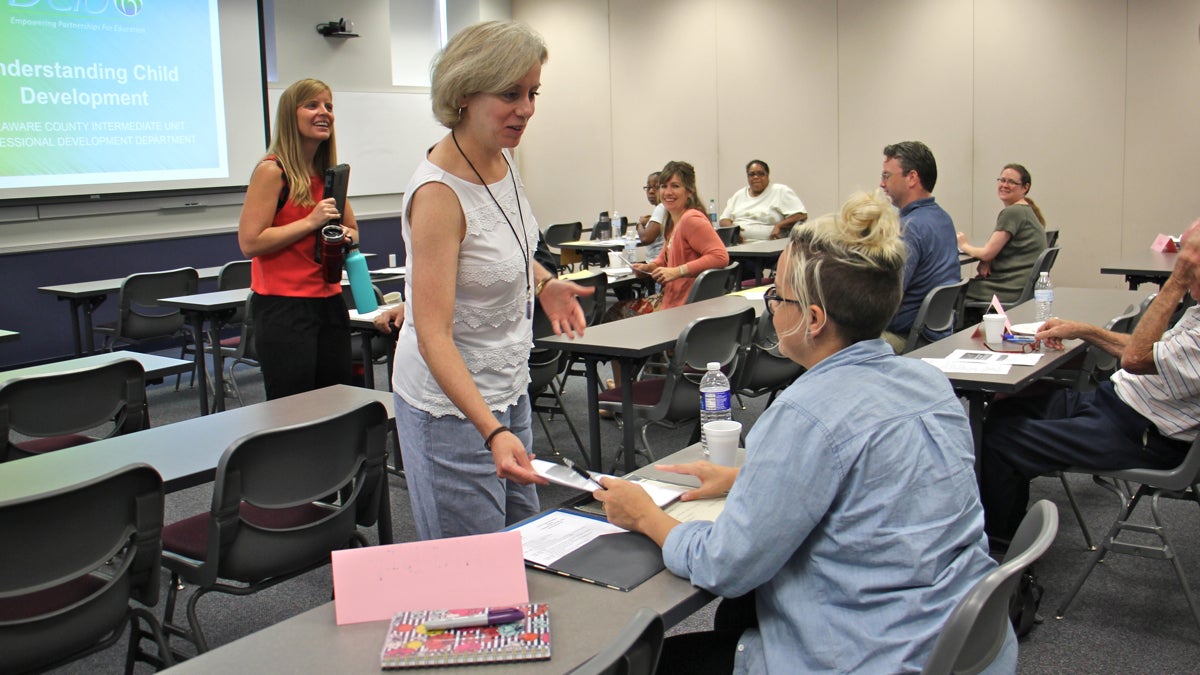 Professional development specialist Nora Connell hands out materials during a class for prospective substitute teachers at Delaware County Intermediate Unit. (Emma Lee/WHYY)