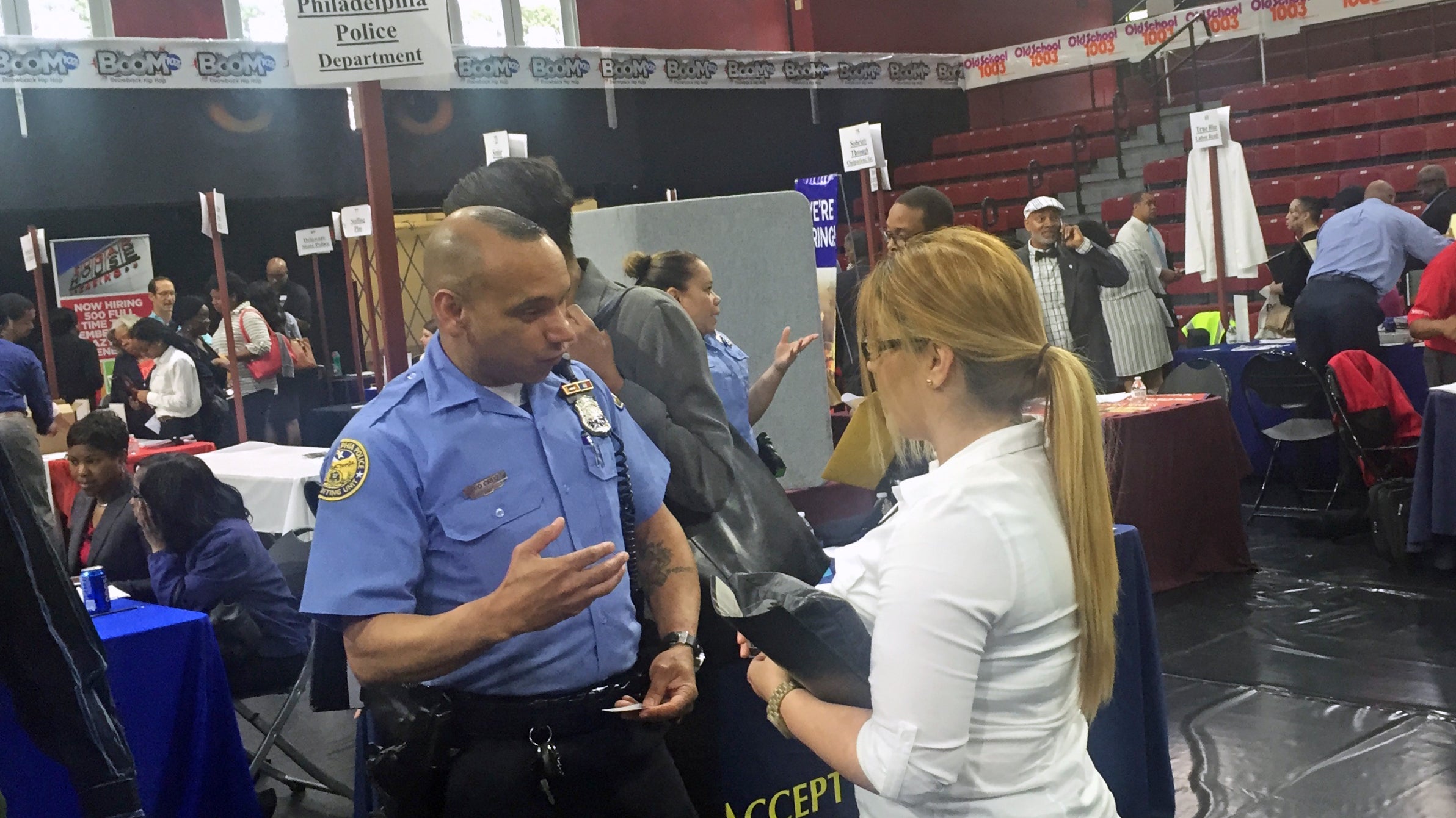 Officer Samuel Cruz with the Philadelphia Police Department's recruiting division chats with a would-be recruit at a job fair at Temple University.(Bobby Allyn/WHYY)