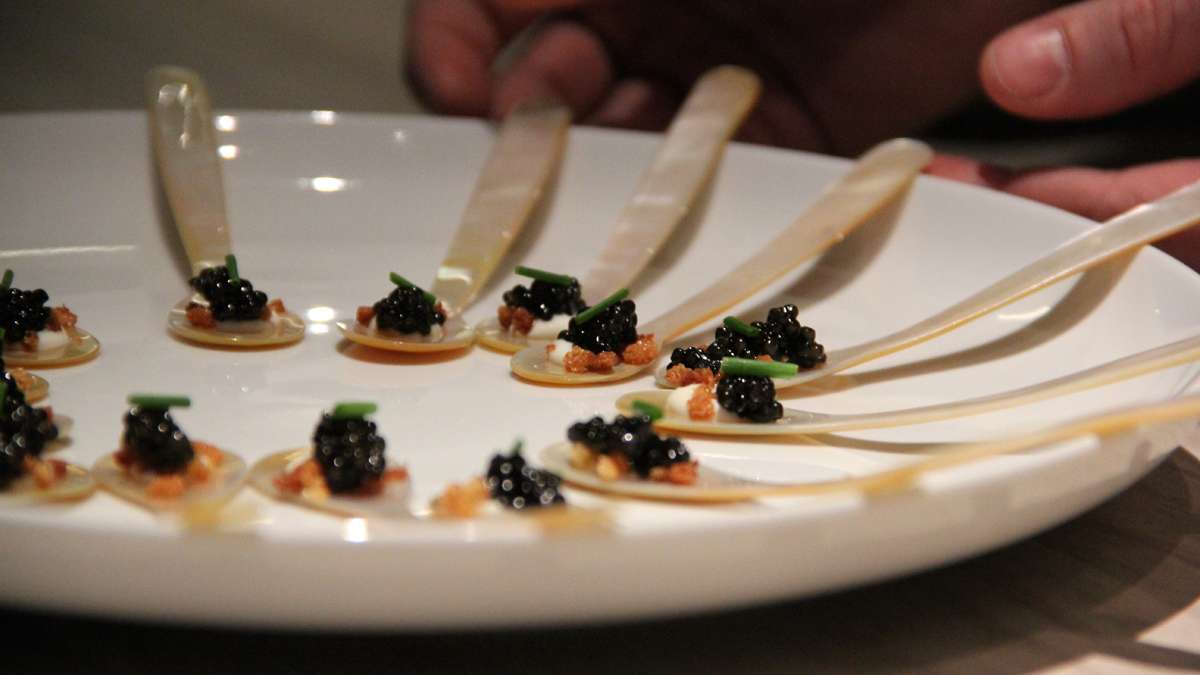 A waitress serves caviar on mother-of-pearl spoons at Jose Garces' Volver in 2014. (Emma Lee/WHYY)