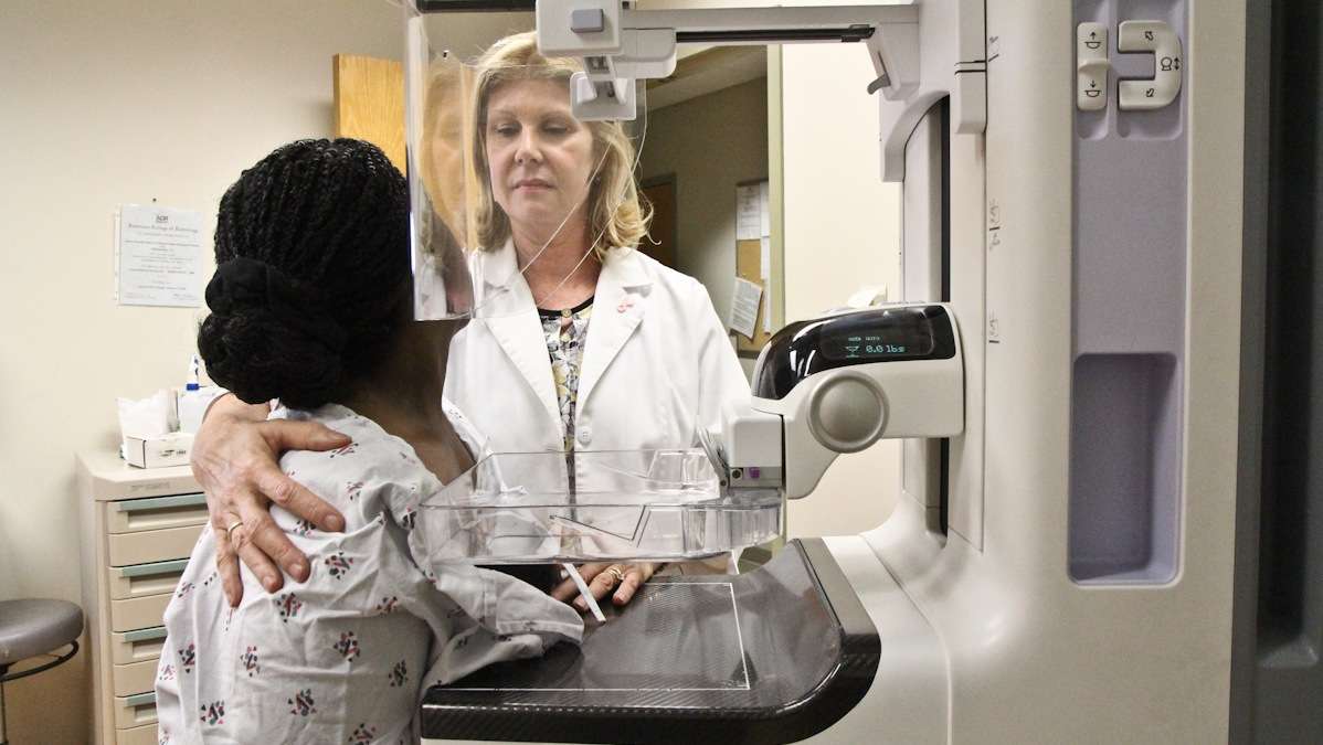  Chief technician Donna Burke demonstrates how a mammogram is given with the help of Sharon Born, the manager of the Women's Center. (Kimberly Paynter/WHYY) 