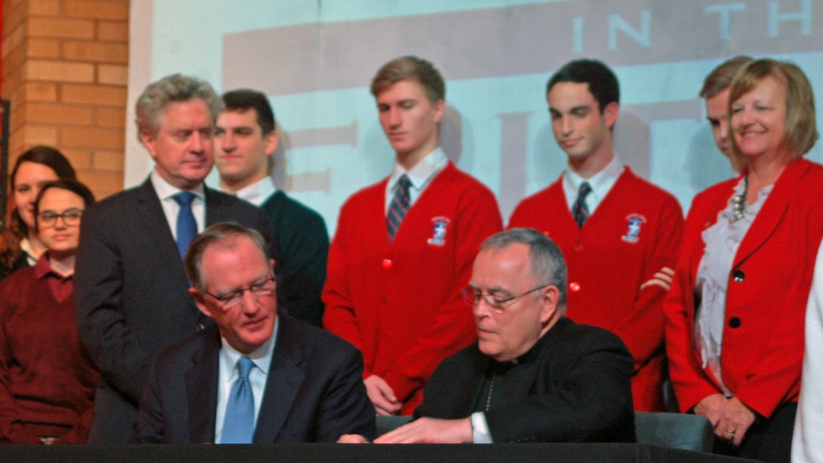 At Archbishop Ryan High School in Philadelphia, Faith in the Future board chairman Ed Hanway, left,  and Archbishop Charles Chaput sign the management agreement. (Sara Hoover/for NewsWorks) 