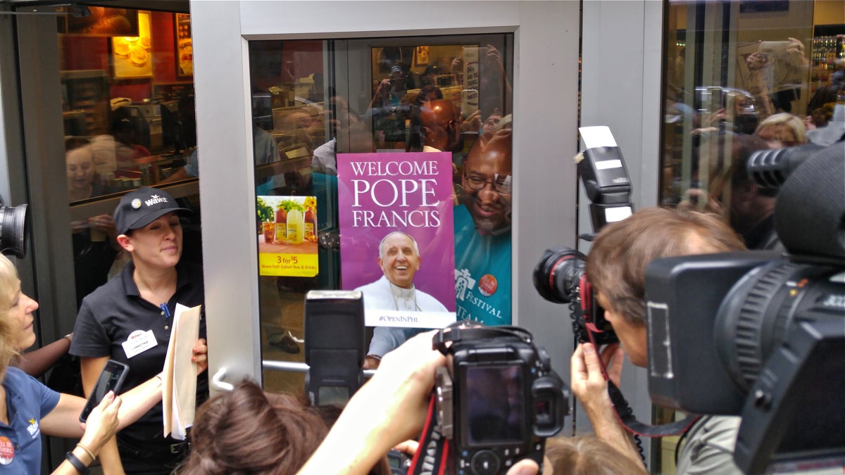  Mayor Michael Nutter puts up a sign at a Center City Wawa letting customers know it will remain open through the pope's visit to Philadelphia. (Tom MacDonald/WHYY) 
