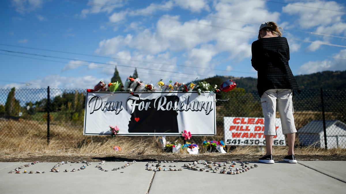  A woman visits a makeshift memorial near the road leading to Umpqua Community College Saturday, Oct. 3, 2015, in Roseburg, Ore. Armed with multiple guns, Chris Harper Mercer, 26, walked in a classroom at the community college, Thursday, and opened fire, killing several and wounding several others. (AP Photo/John Locher) 