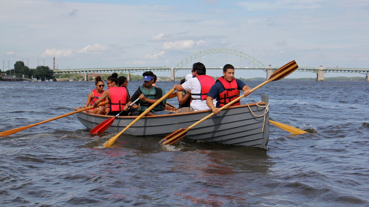 WorkReady students paddle on the Delaware River in a boat they built as part of the Wooden Boat Factory summer youth employment program. (Emma Lee/WHYY)