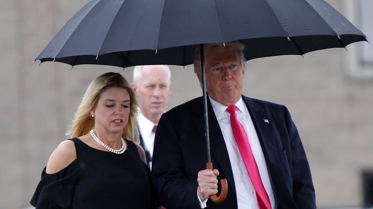 Republican presidential candidate Donald Trump walks in the rain with Florida Attorney General Pam Bondi