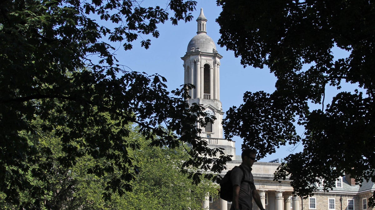 A Penn State University student walks across campus in front of Old Main on main campus in State College