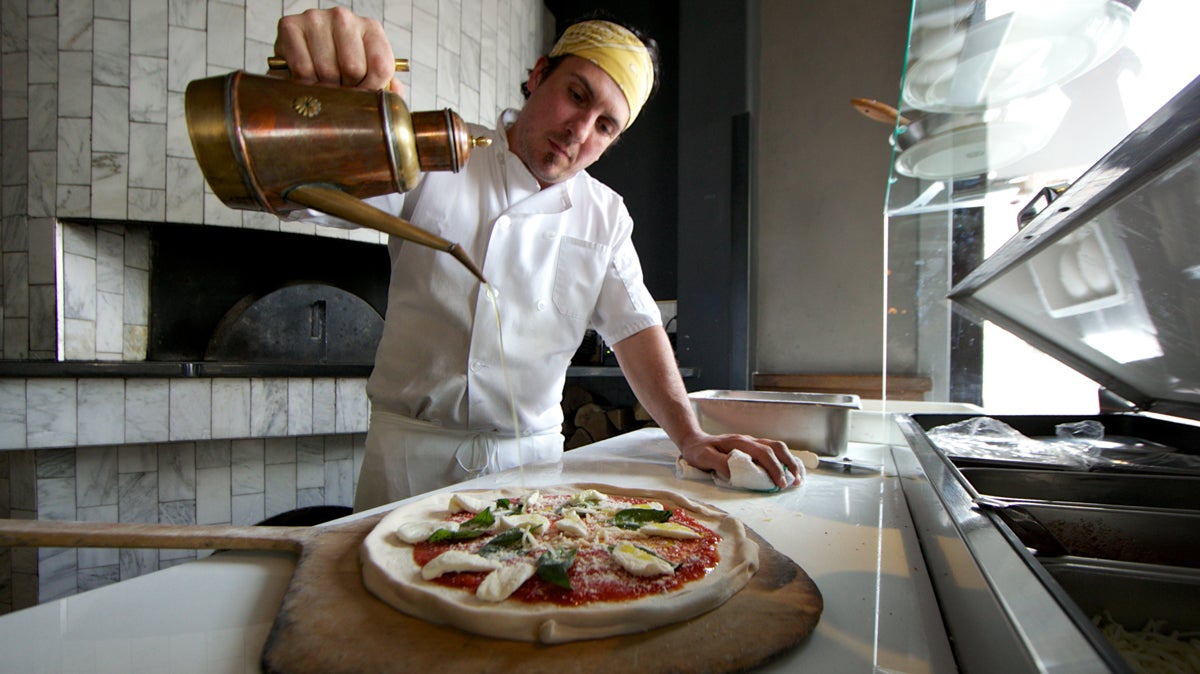 Chef Luca Sena Jr. at Revolution House, adds the finishing touches to a pizza before putting it into the wood burning oven (Nathaniel Hamilton/for NewsWorks) 