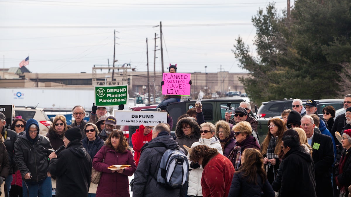 The sole counter protestor, Jim O'Connor, sat on the roof of his car behind approximately 120 pro-life protestors calling for the defunding of Planned Parenthood in Warminster, Pa Saturday morning. (Brad Larrison for NewsWorks)