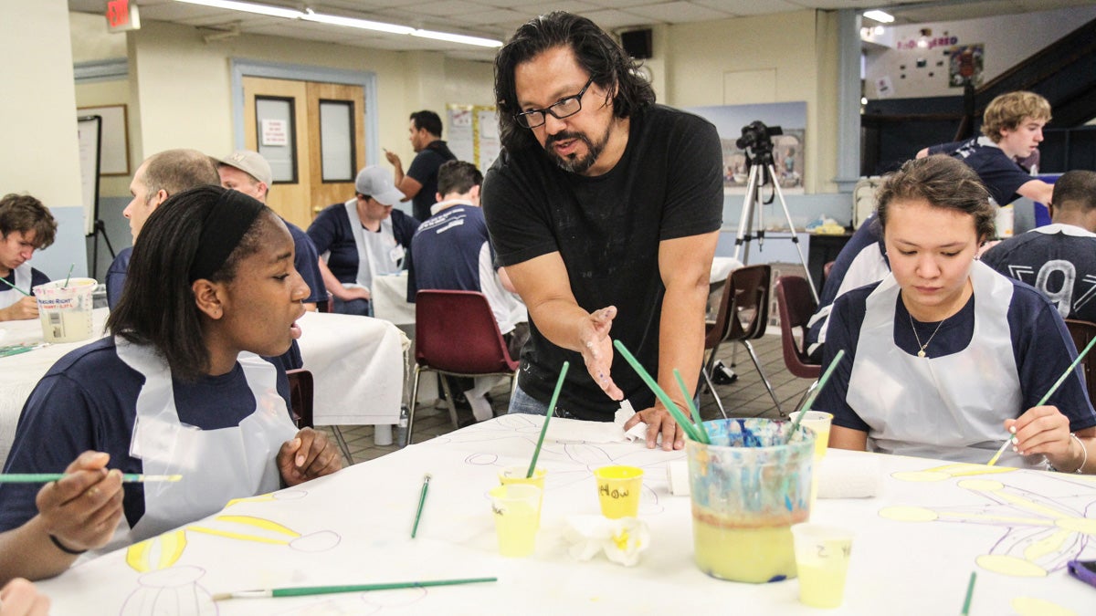 Cesar Viveros, the Pope Francis mural’s leading artist, instructs high schoolers participating the mural’s Paint Day. (Kimberly Paynter/WHYY)