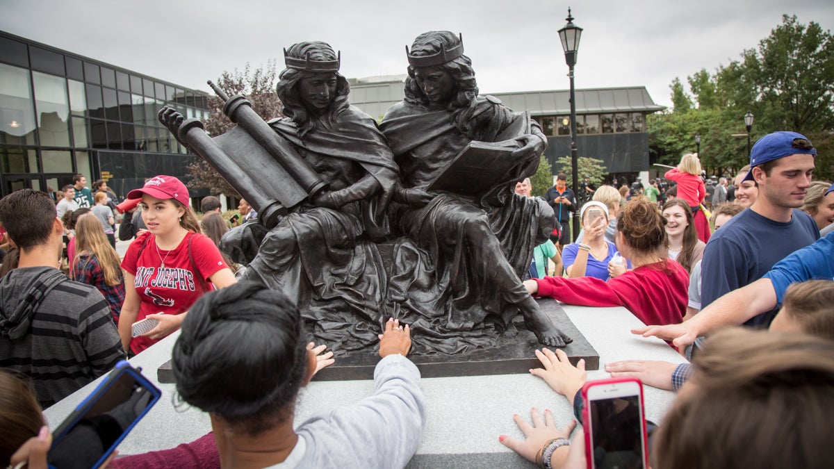  Students and locals touch the statue honoring the 50th anniversary of the 1965 Second Vatican Council declaration Nostra Aetate which was just blessed by Pope Francis in an unscheduled and surprise visit to St. Joseph's University. (Emily Cohen/for NewsWorks) 