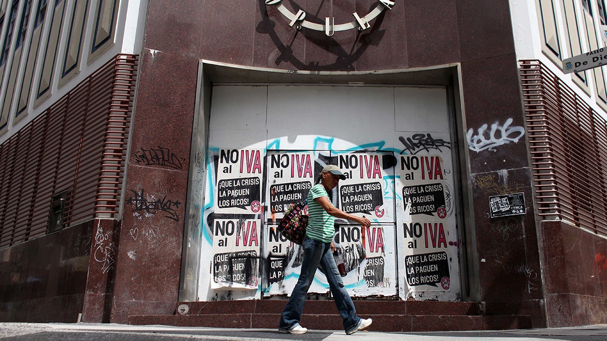 A woman walks in front of a closed down bank in the neighborhood of Rio Piedras in San Juan