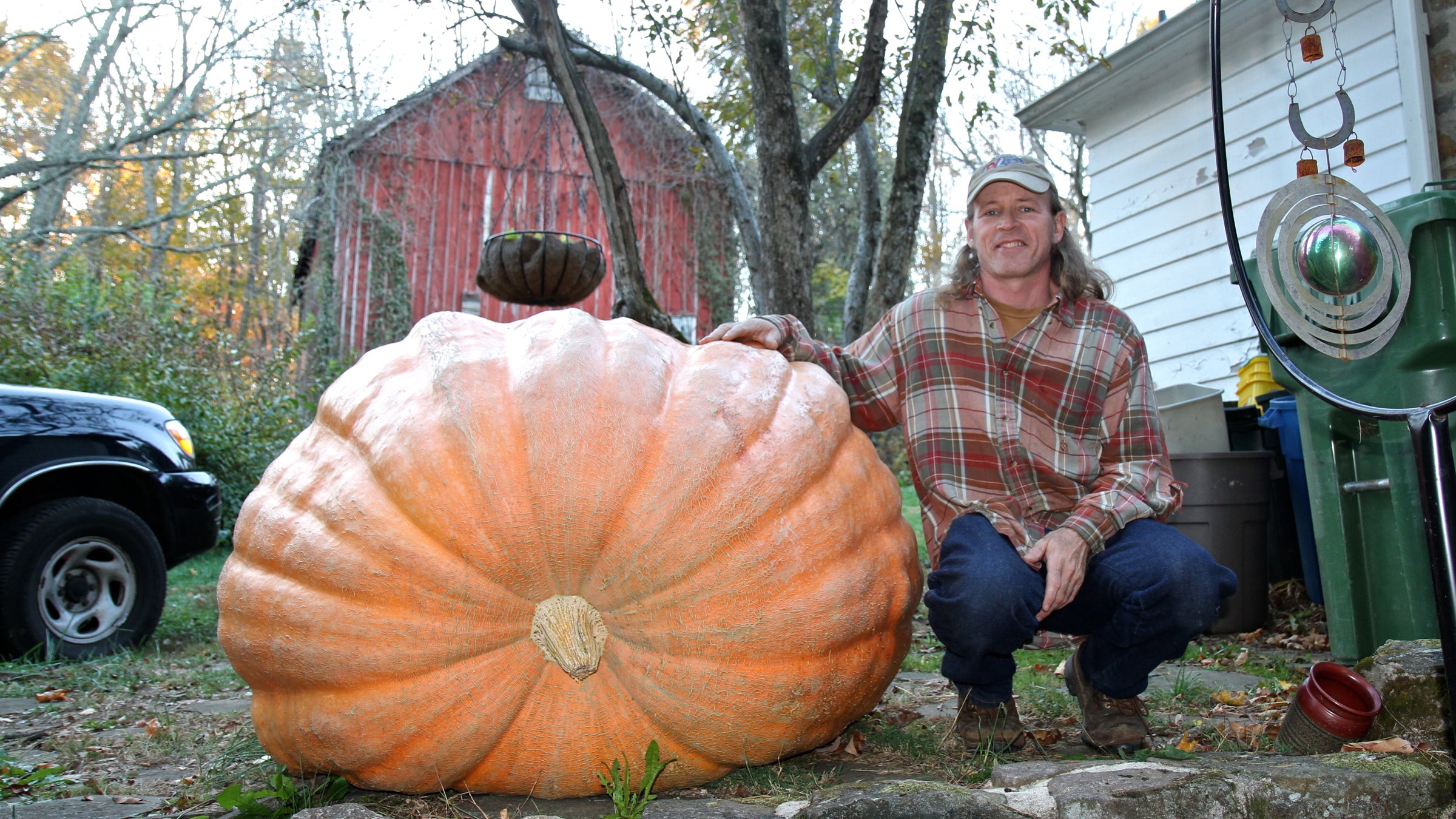 Alex McCracken shows off a giant pumpkin that mysteriously stopped growing early in the season at his Quakertown home. (Carolyn Beeler/WHYY)