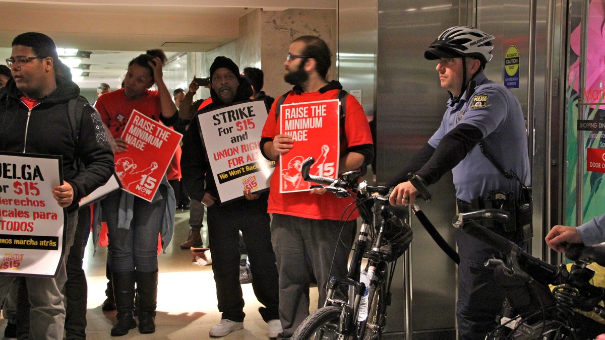  Philadelphia police block  demonstrators rallying for a minimum-wage hike from entering the food court at the Comcast building Tuesday. (Emma Lee/WHYY) 