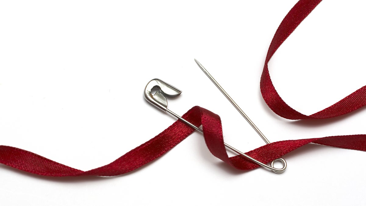 (<a href='http://www.bigstockphoto.com/image-26363870/stock-photo-safety-pin-and-red-ribbon'>pcatalin</a>/Big Stock Photo)