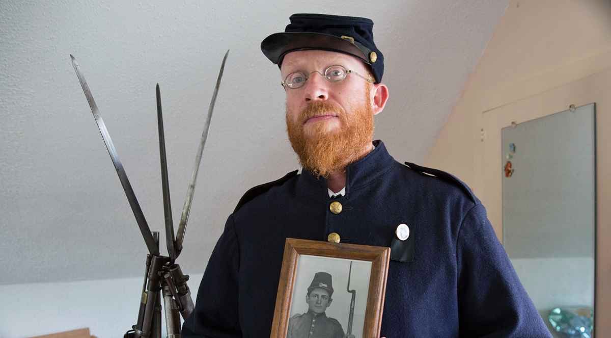 Civil war re-enactor preparing to take part in the 150th  anniversary of the Battle of Gettysburg.  He holds a photo of his great-great-great-grandfather who fought in the war. (Lindsay Lazarski/WHYY)