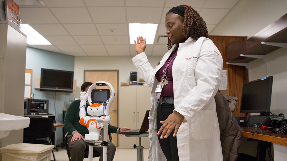 A small humanoid robot leads Dr. Michelle Johnson