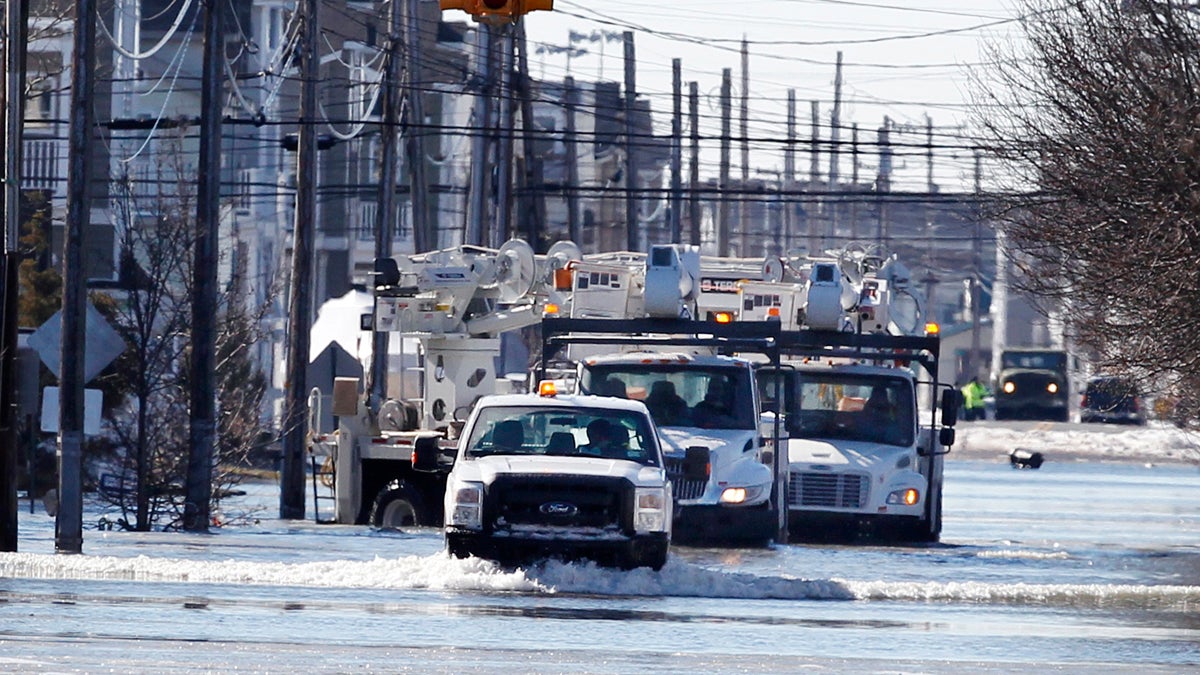  Crews drive a caravan of utility repair trucks on flooded streets early Sunday, Jan. 24, 2016, in Sea Isle City, N.J.  (AP Photo/Mel Evans) 