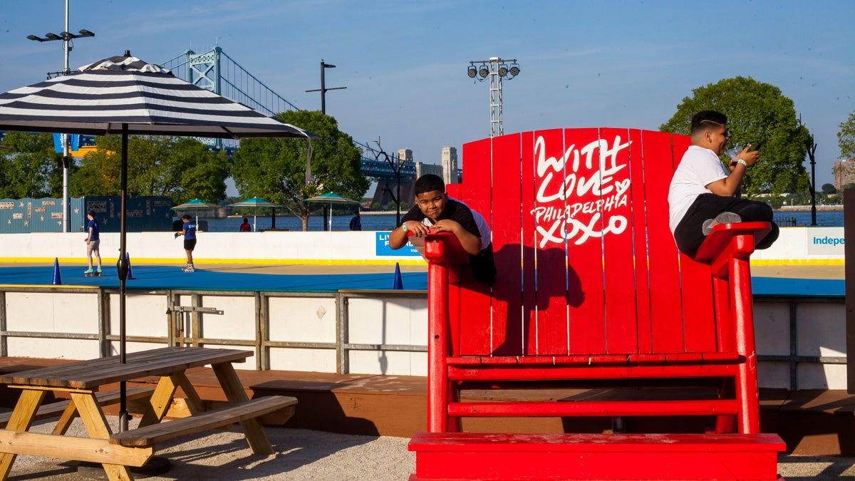 Jeiemai Floyd,7, at left and his brother Elyjah Floyd,12, hang out on the oversized chair at the River Rink at Penn's Landing. (Brad Larrison for NewsWorks)