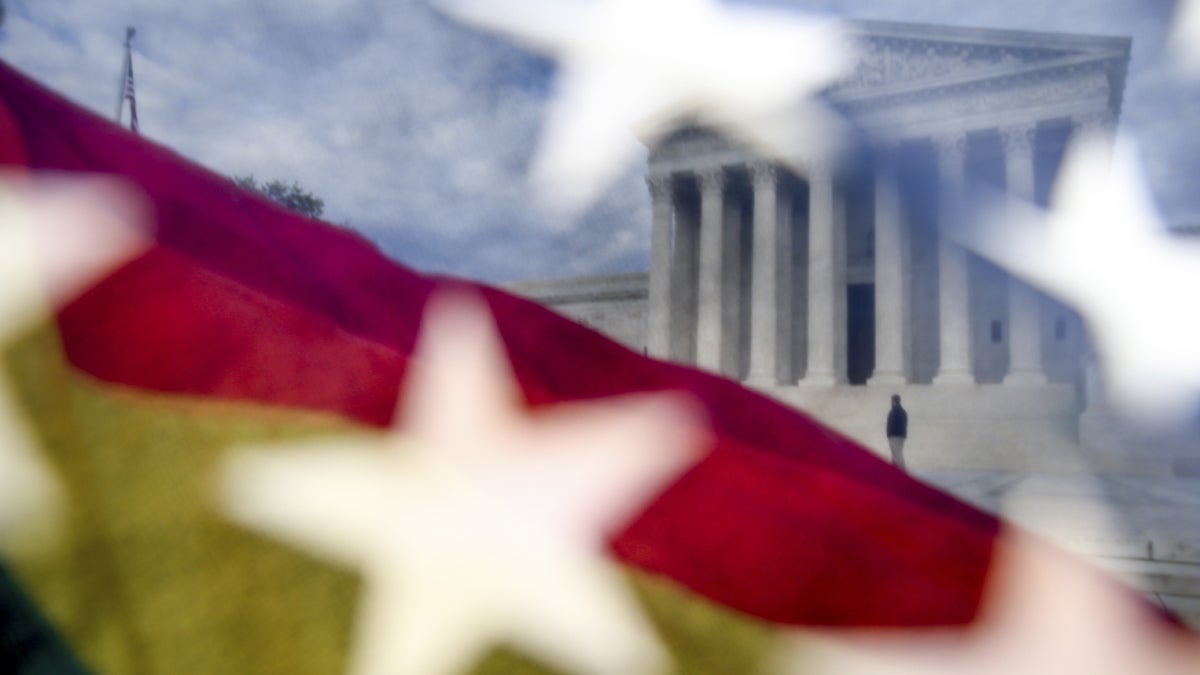  A rainbow flag, seen through an American flag, flies in front of the Supreme Court in Washington on April 27, 2015, as the Supreme Court begins to hear arguments in cases that could make same-sex marriage the law of the land. (AP Photo/Andrew Harnik) 
