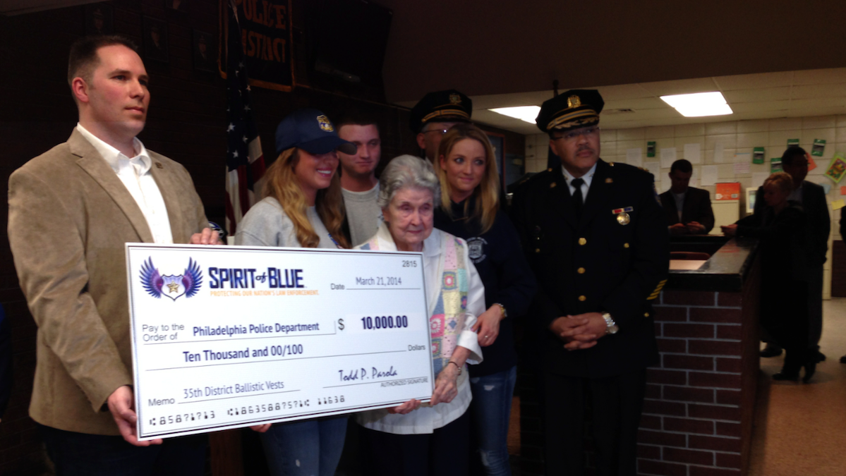  Relatives of slain Philadelphia Police Officer Chuck Cassidy joined with department officials to accept a $10,000 grant from Spirit of Blue Foundation representative Ryan Smith (left) on Friday. (Brian Hickey/WHYY) 