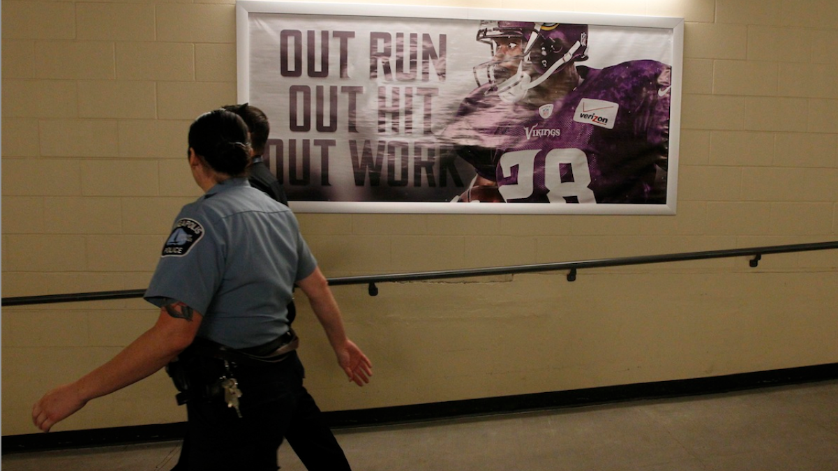  A member of the Minneapolis police department walks past a photo of Minnesota Vikings running back Adrian Peterson before the start of the Vikings/Patriots on Sunday. Peterson was indicted in Texas on Friday for using a branch to spank one of his sons. (AP Photo/Ann Heisenfelt) 