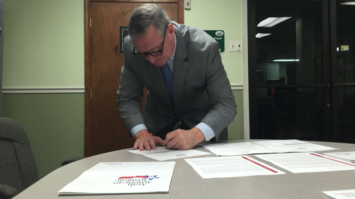  Mayoral candidate Jim Kenney signs the 'Pledge to Combat Bigotry' at the Al-Asqa mosque during Friday morning's Eid al-Fitr celebration. (Brian Hickey/WHYY) 