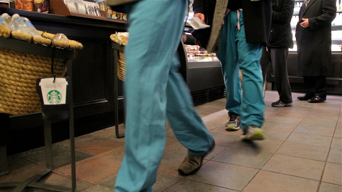 Hospital workers wear their scrubs into a coffee shop at 10th and Chestnut streets in Philadelphia. (Emma Lee/WHYY)