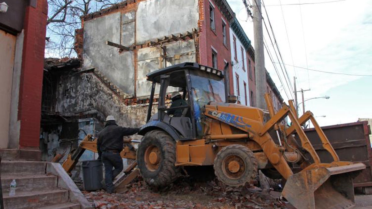 Workers demolish a North Philadelphia rowhouse. (Emma Lee/WHYY) 