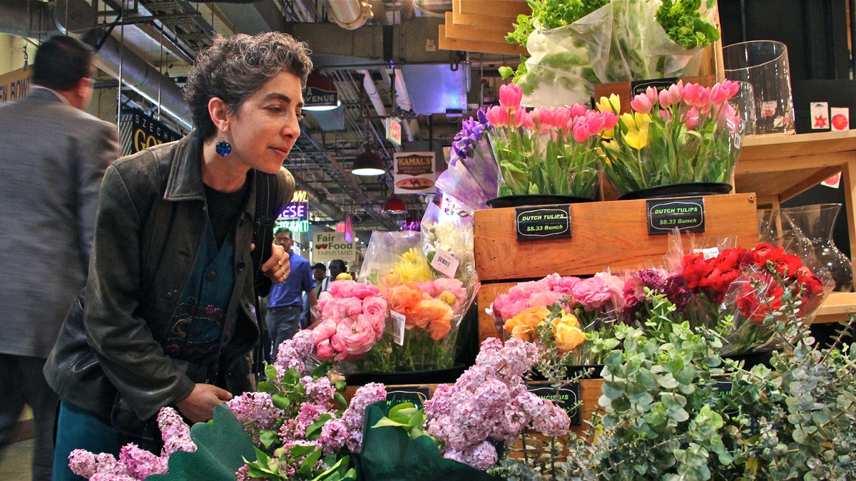 At Market Blooms in Reading Terminal Market Anndee Hochman attempts to smell the aromas of lilac and eucalyptus. (Emma Lee/for NewsWorks)