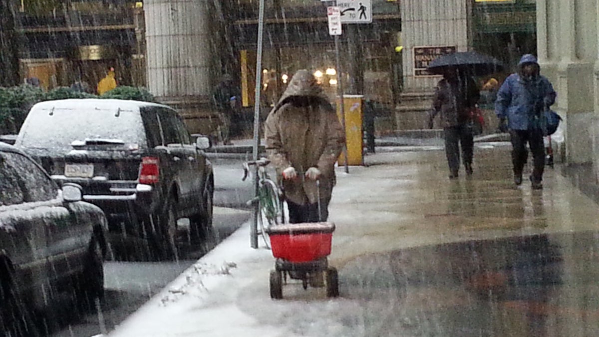  A worker keeps the sidewalks at Broad and Market streets salted early Monday. (Tom MacDonald/WHYY) 